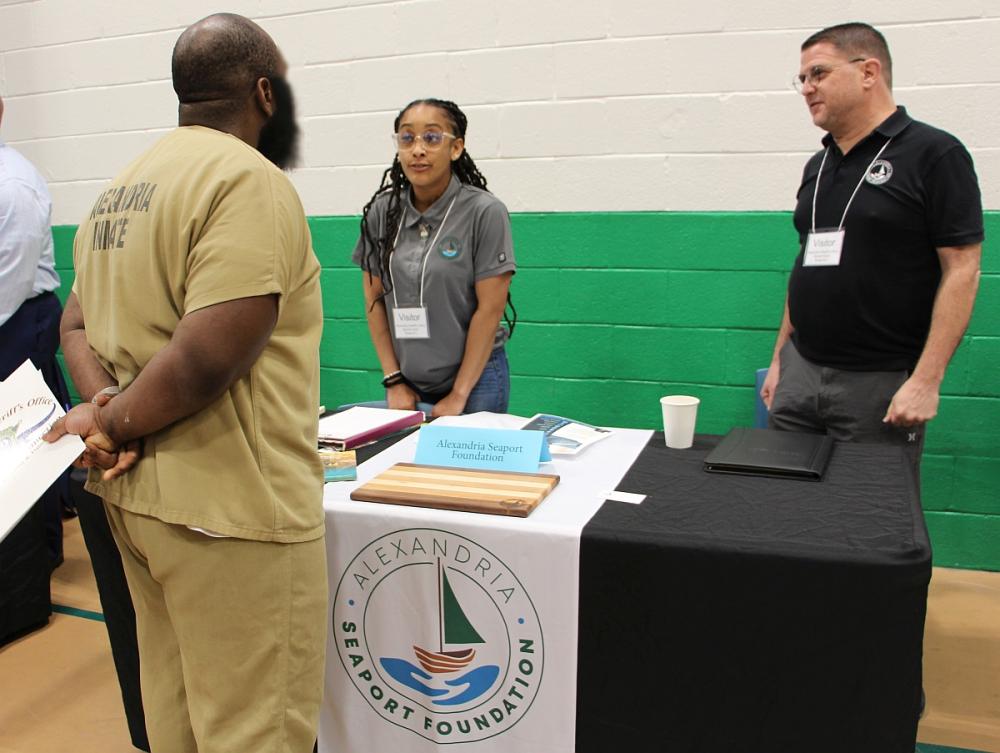 Inmate in khaki uniform at a table speaking with two organization members on the other side of the table
